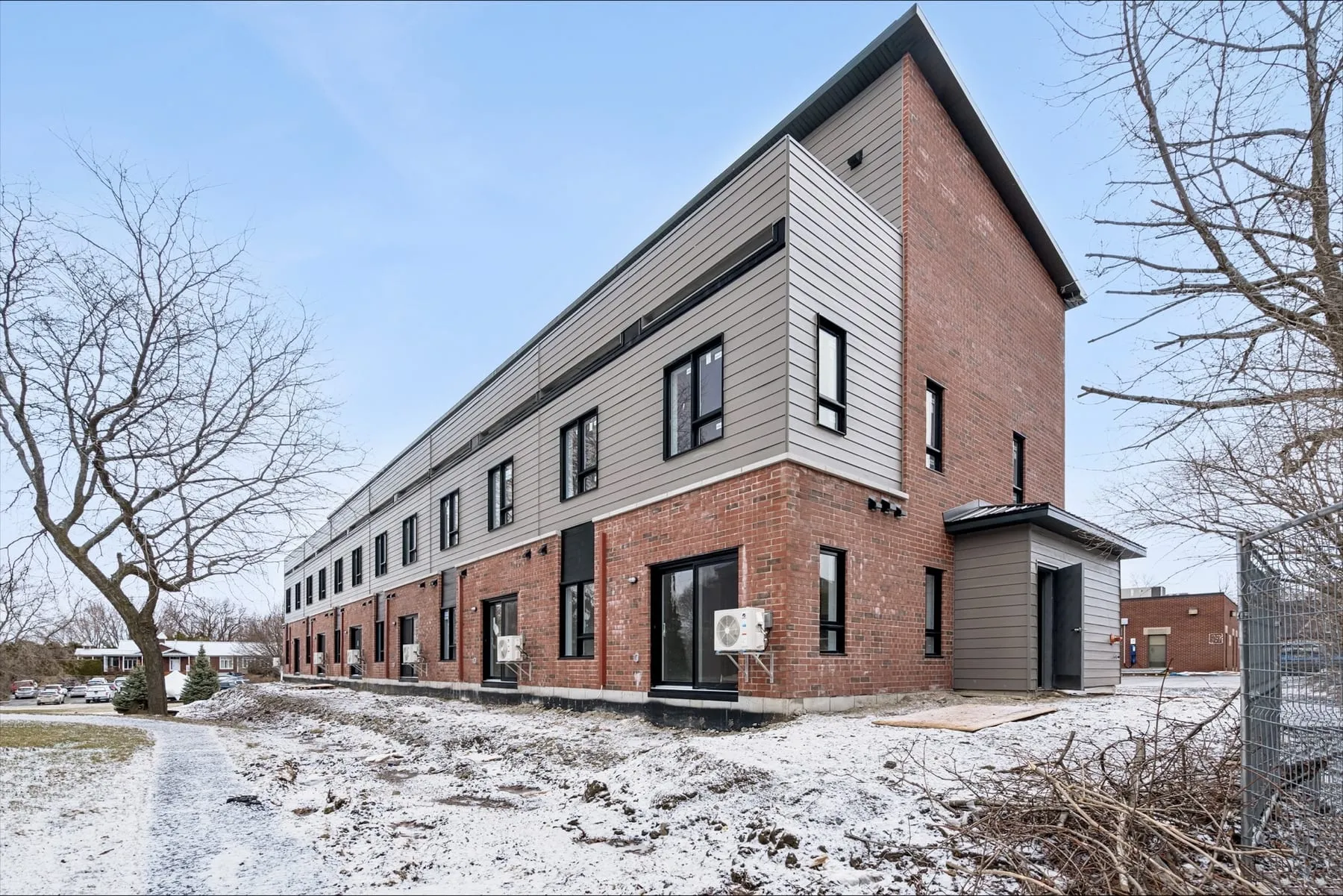 Le bâtiment vu d'angle, qui montre toute sa longueur en brique et revêtement gris