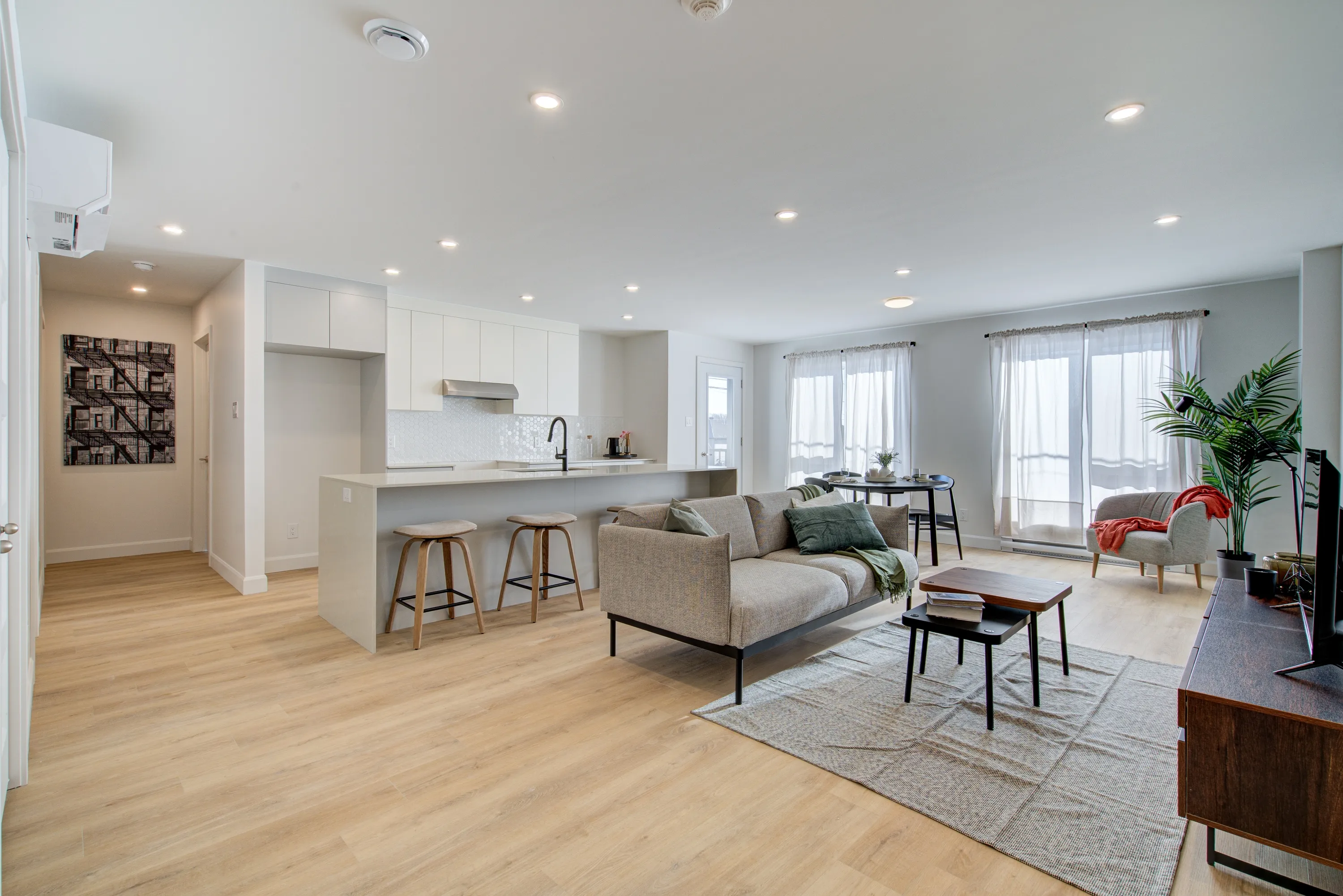 Séjour et cuisine d'un logement livré, lumière naturelle sur trois fenêtres