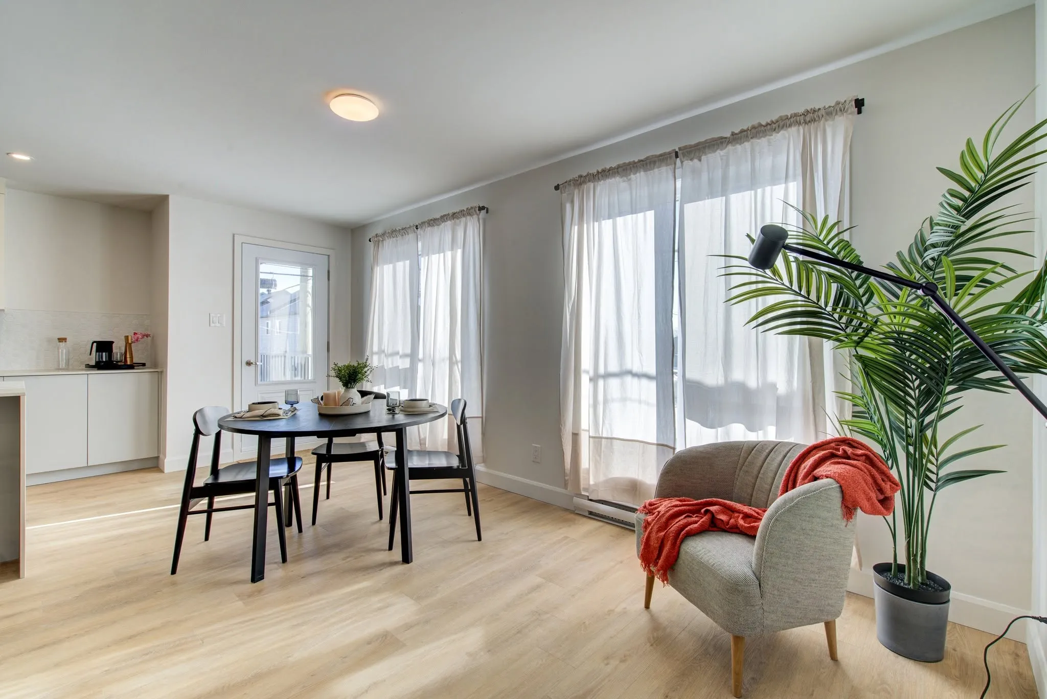 Coin repas meublé et porte-balcon, cuisine à l'arrière-plan